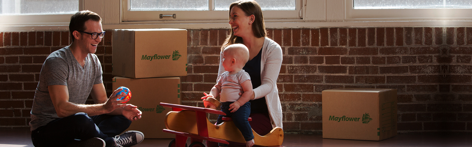 Family of 3 smiling and moving boxes