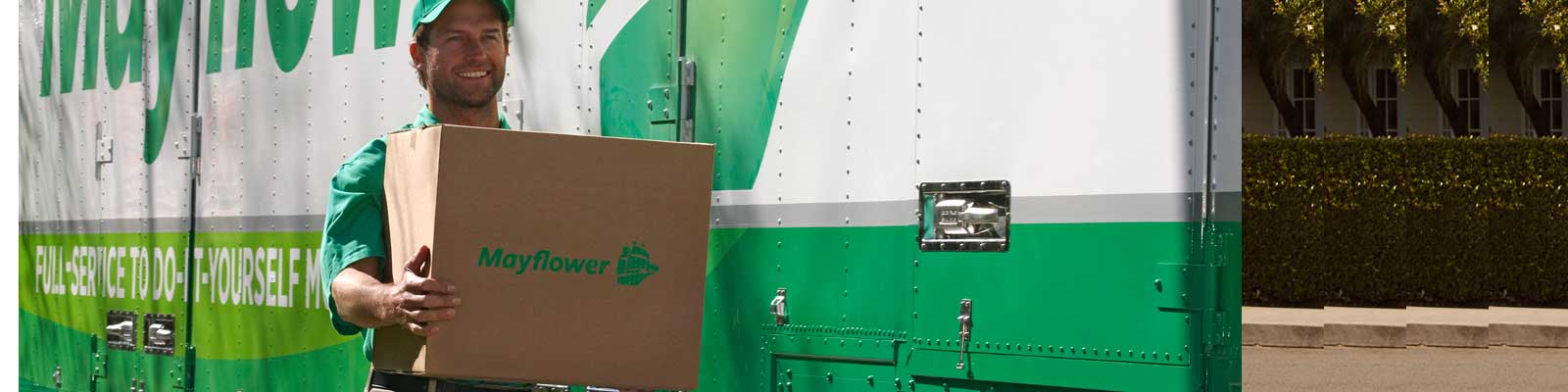 Smiling mover holding a box outside a Mayflower truck